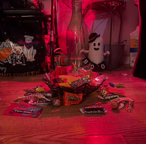 Bowl with candy spilling out on ground with pretty lights. 