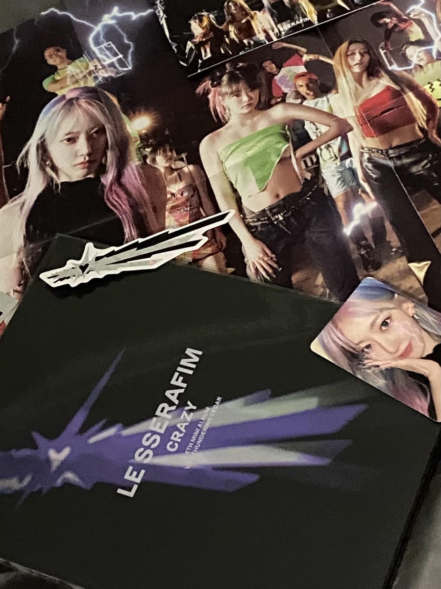 Picture of LE SSERAFIM album named 'CRAZY'. Included in the photo is the album cover, poster, sticker, and randomized photocard of a member.